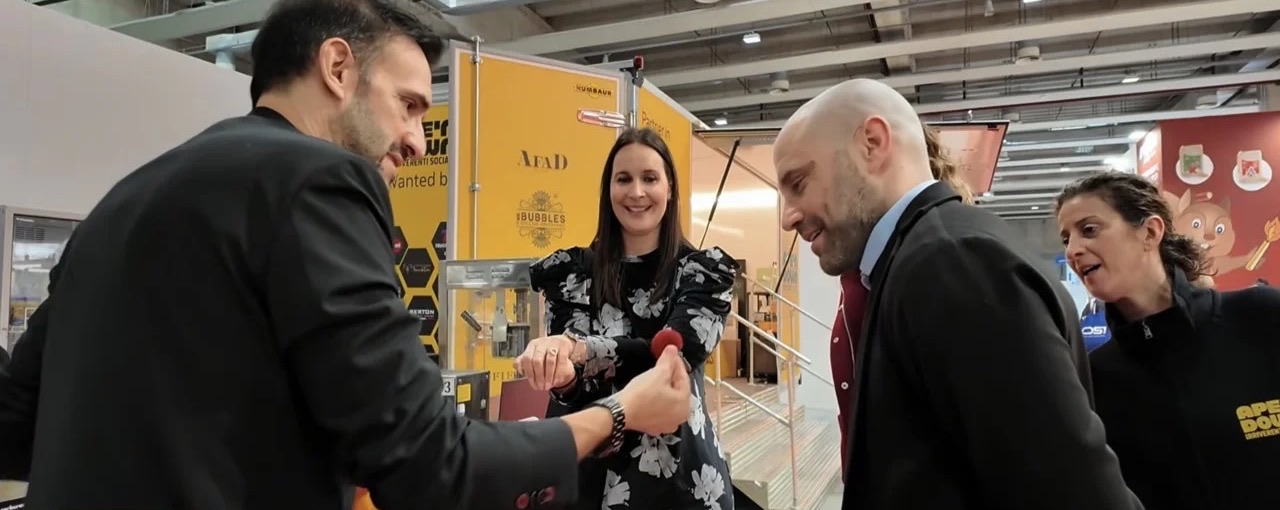 Il mago Sergio Starman ferma i visitatori davanti a uno stand in fiera con un gioco di palline