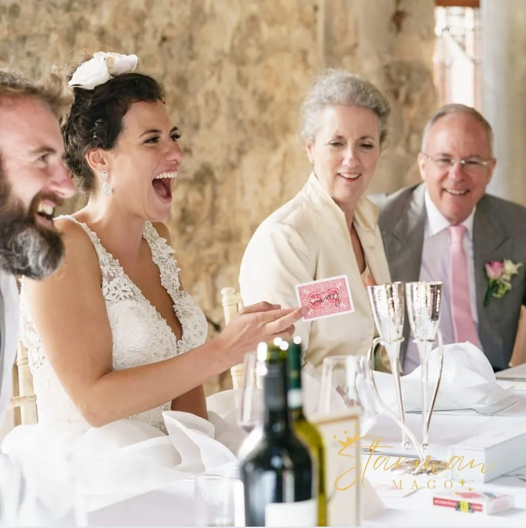 Una sposa ride tenendo in mano una carta durante un gioco di magia al tavolo